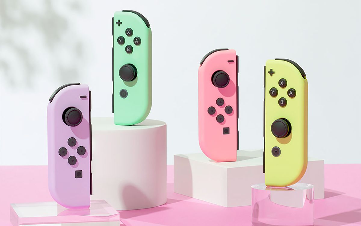 Four Nintendo Switch Joy-Cons in pastel colors standing upright on opaque white and transparent acrylic stands