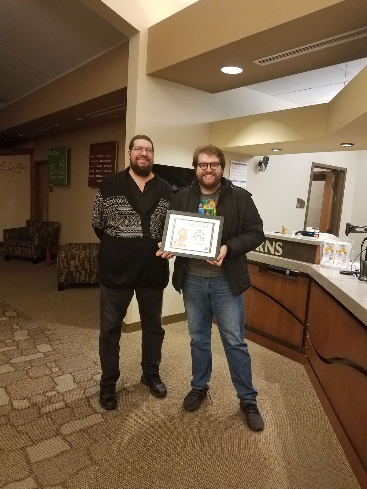 Russ and Quinton Hoover standing next to each other with a framed drawing of Garfield.