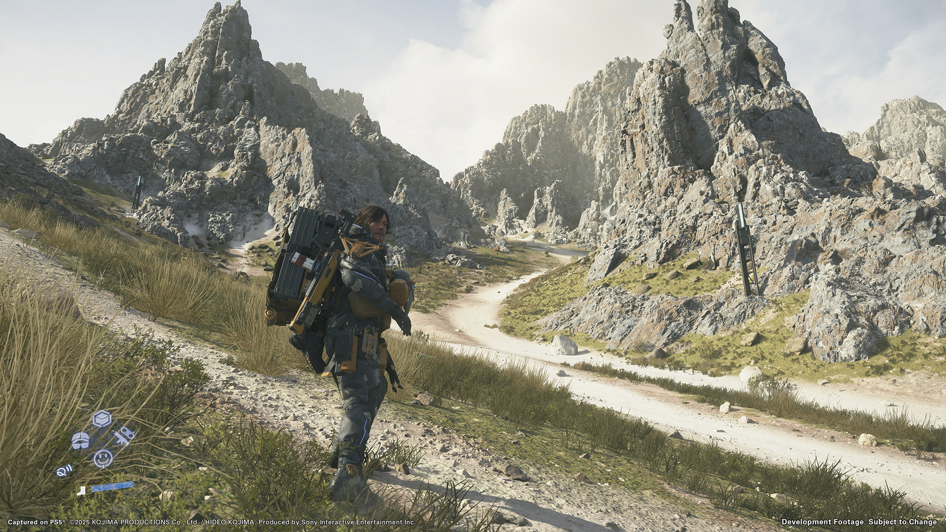 Sam crosses between two cliffs on a path in Death Stranding 2: On the Beach.